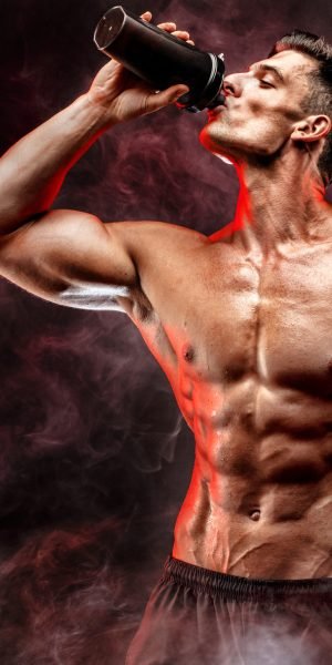 Muscular,Man,With,Protein,Drink,In,Shaker,Over,Dark,Smoke